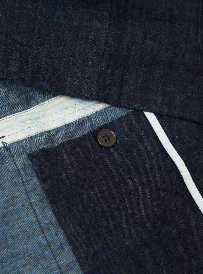 Close-up of the Indigo Brushed Denim Labour Jacket showing the denim texture, button, and white trim. The jacket is neatly arranged on a flat surface.