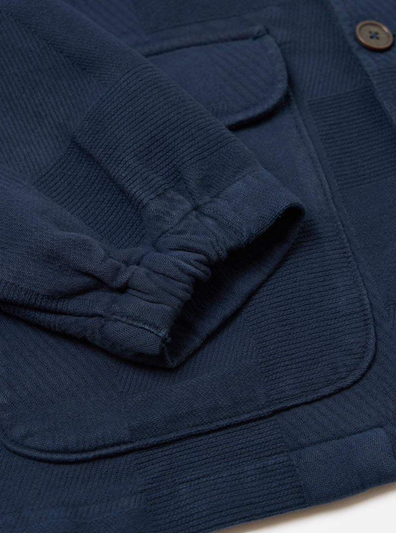 Close-up of the Dark Navy Patchwork Weave Cotton Labour Jacket showing the sleeve, pockets, and textured cotton weave on a white surface.