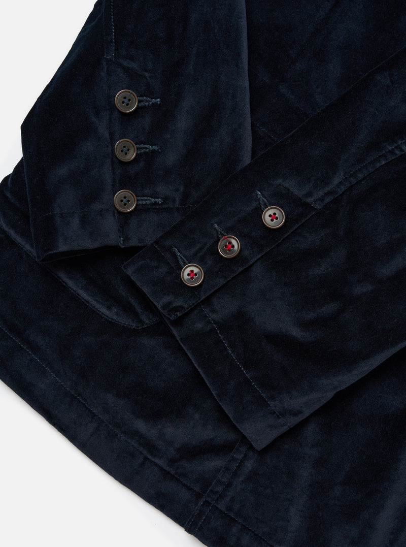 Close-up of the navy velveteen Manor Jacket on a white surface. Shows the jacket's buttons and soft texture. The jacket is neatly folded, highlighting its tailored fit.