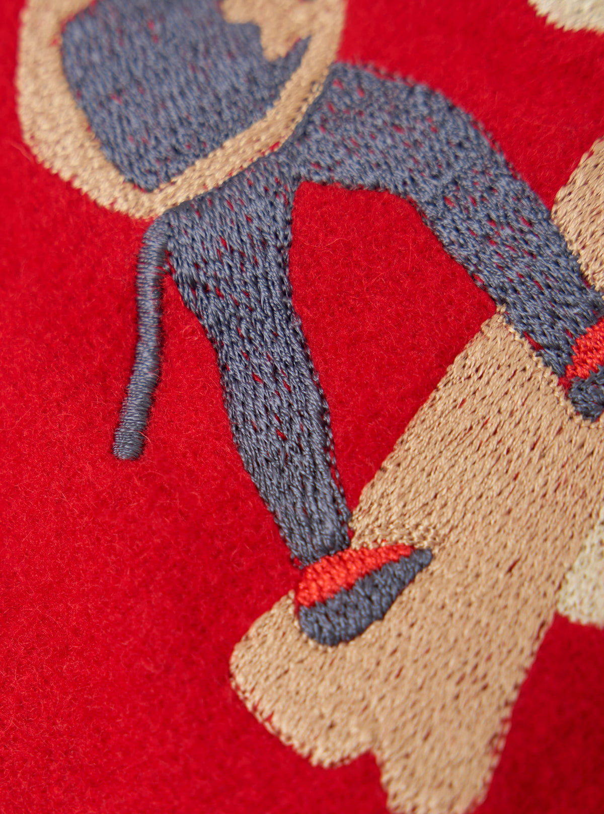 Close-up of the Embroidered Red Mowbray Military Fatigue Jacket, showing detailed stitching in blue, tan, and red on the jacket's red fabric.