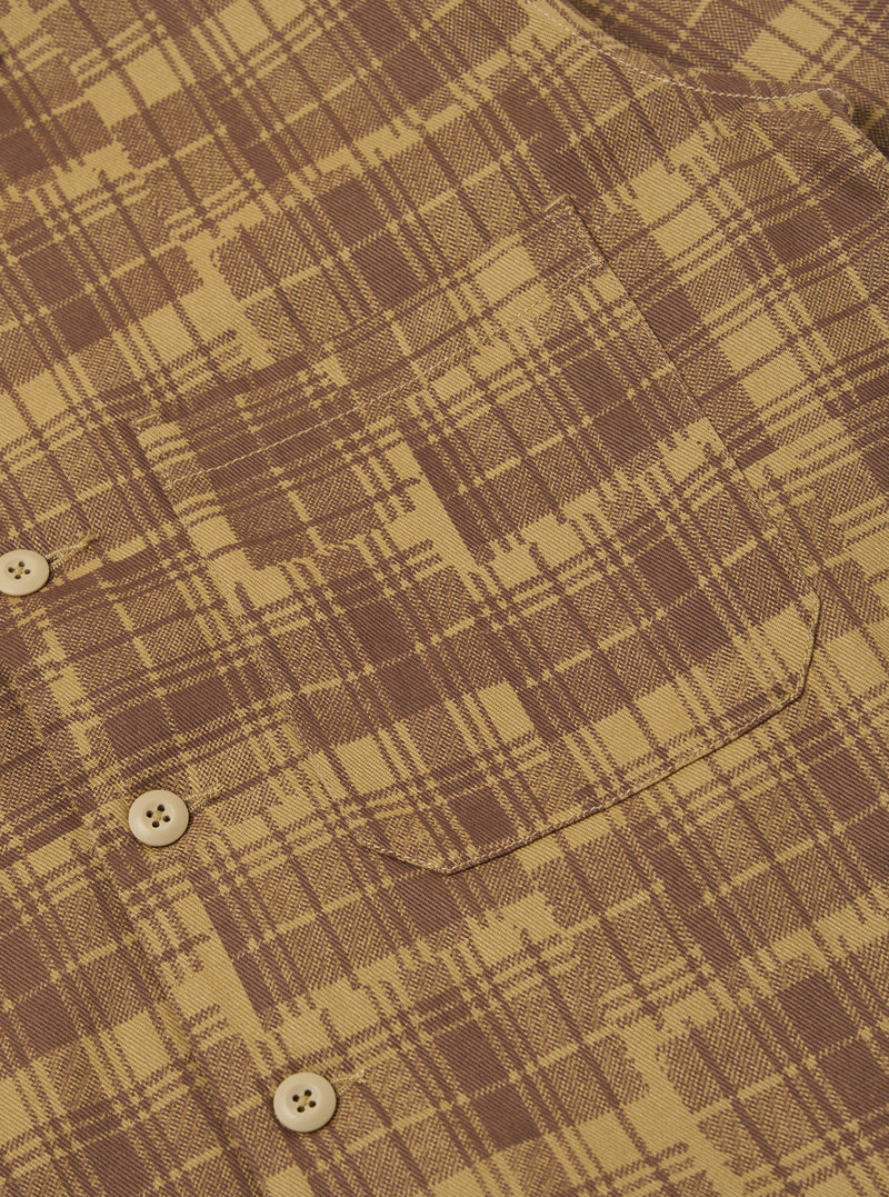 Close-up of the Khaki Patch Check Twill Fatigue Shirt. The shirt features a brown and khaki check pattern, a chest pocket, and button closure. Shot on a flat surface.