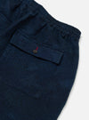 Close-up of the Black/Indigo Denim Camo Braga Pant on a white surface. The denim has a subtle camo pattern and a back pocket with a button closure.