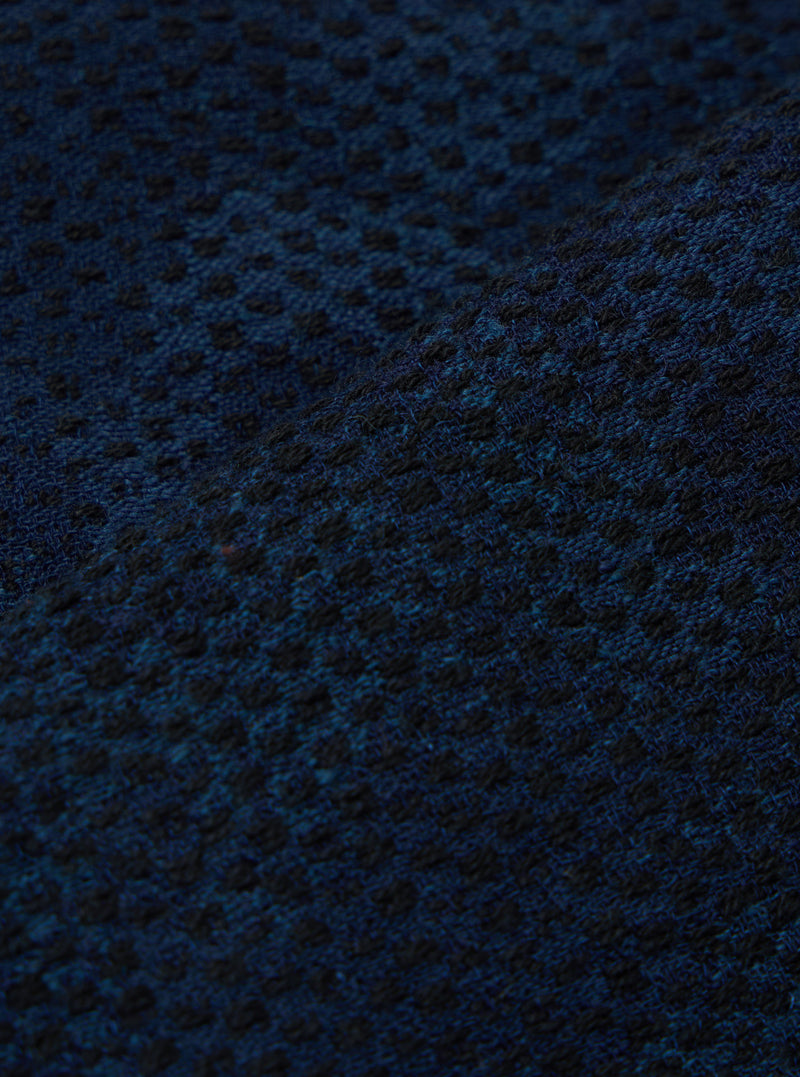 Close-up of the Black/Indigo Denim Camo Braga Pant fabric. The material has a subtle camo pattern in black and indigo. The fabric is textured and folded.