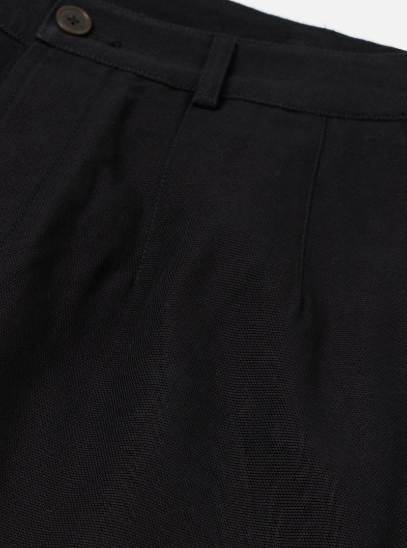 Close-up of the Black Organic Canvas Dutch Pant. Details include the button, belt loop, and pleats. The fabric is a dark canvas. Shot on a white background.