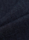 Close-up of the Indigo Brushed Denim Oxford Pant fabric. The indigo denim has a soft, brushed texture. Shot on a plain surface to highlight the material.