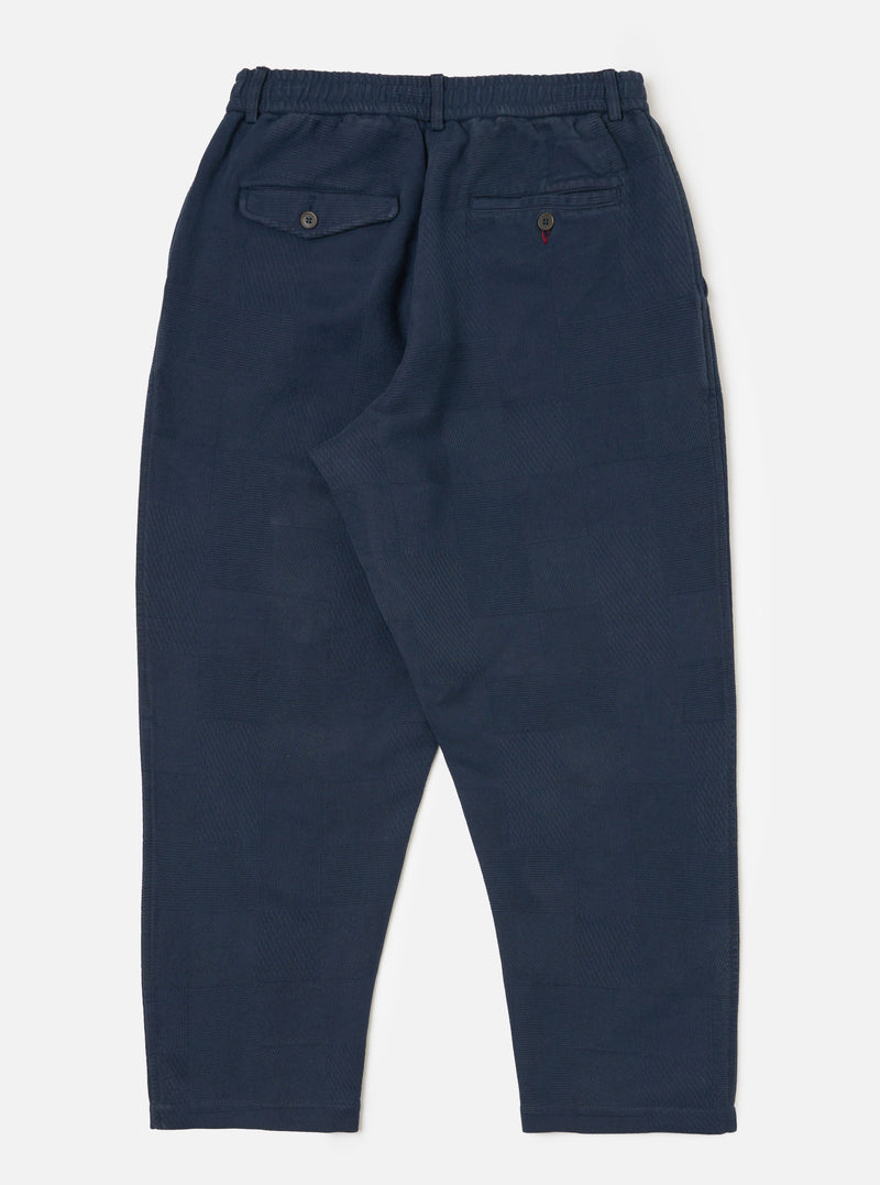 Dark navy patchwork weave cotton pleated track pant laid flat on a white background. The pants have an elastic waistband and two back pockets.