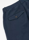Close-up of the Dark Navy Patchwork Weave Cotton Pleated Track Pant on a white surface, showing the textured fabric and buttoned pocket.