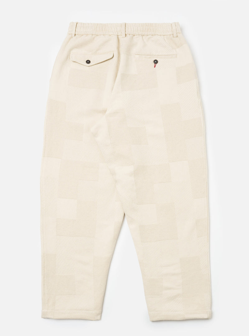 Back view of Ecru Patchwork Weave Cotton Pleated Track Pant on a white background. The pants have a relaxed fit and feature a unique patchwork design.