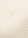 Close-up of the Ecru Patchwork Weave Cotton Pleated Track Pant fabric. The ecru cotton material is woven with a patchwork pattern and pleated texture, displayed on a flat surface.