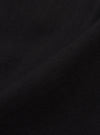 Close-up of the Black Organic Canvas Super Chino fabric. The dark canvas material is textured and folded against a plain background.