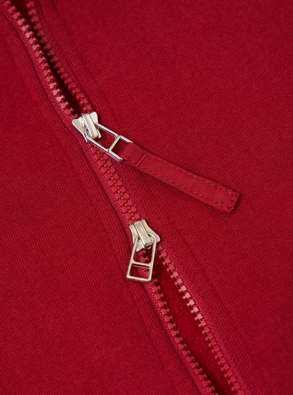 Close-up of the red Brush Back Sweat Tyler Sweat Jacket, showcasing the zipper detail and soft fabric texture. The image is tightly cropped, highlighting the jacket's quality.