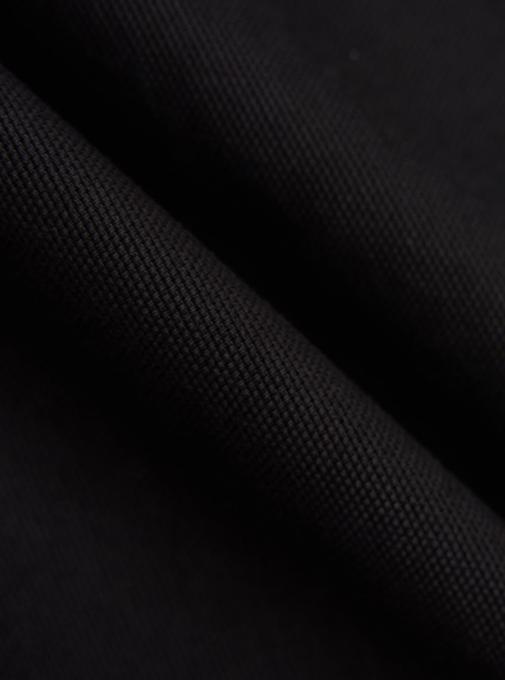 Close-up of the textured black organic canvas fabric of the Dockside Overshirt, showing the material's weave and color.