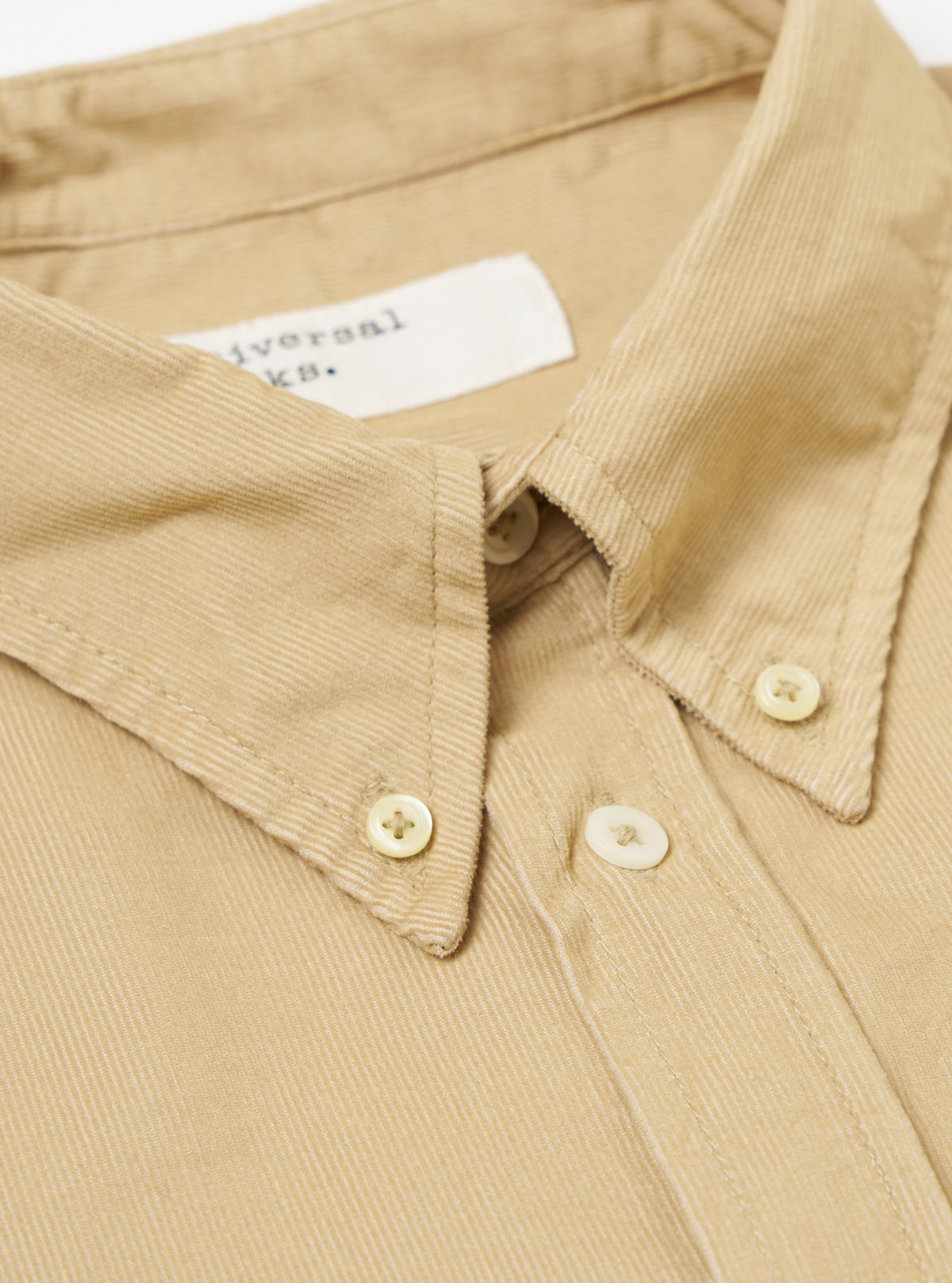 Close-up of the Sand Organic Fine Cord Daybrook Shirt, showing the fine corduroy texture, button-down collar, and light-colored buttons. The shirt is laid flat on a white surface.