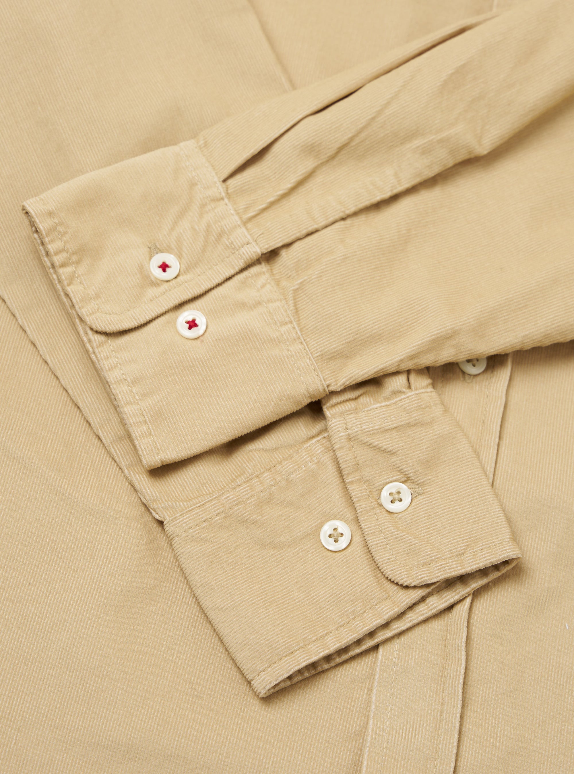 Close-up of the sand-colored Organic Fine Cord Daybrook Shirt, showcasing the fine corduroy texture and button details. The shirt is neatly folded on a neutral surface.