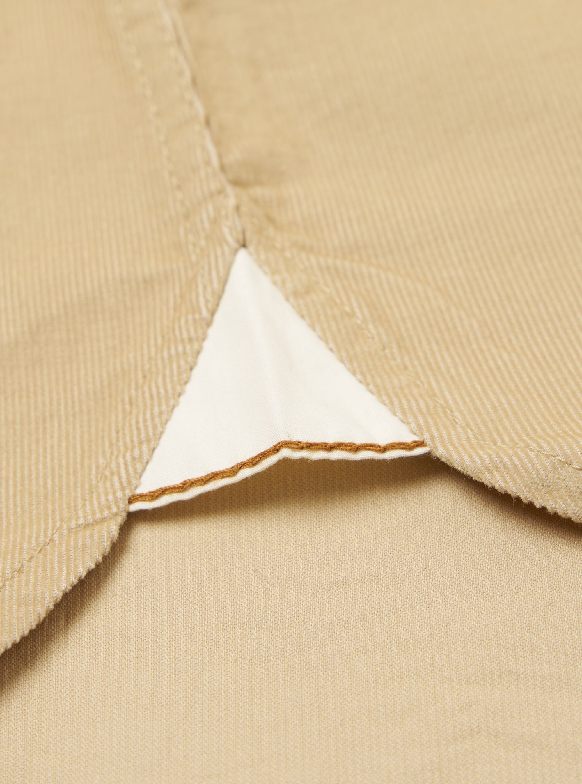 Close-up of the Sand Organic Fine Cord Daybrook Shirt, showcasing the fine corduroy texture and a triangular insert with detailed stitching on a flat, neutral background.