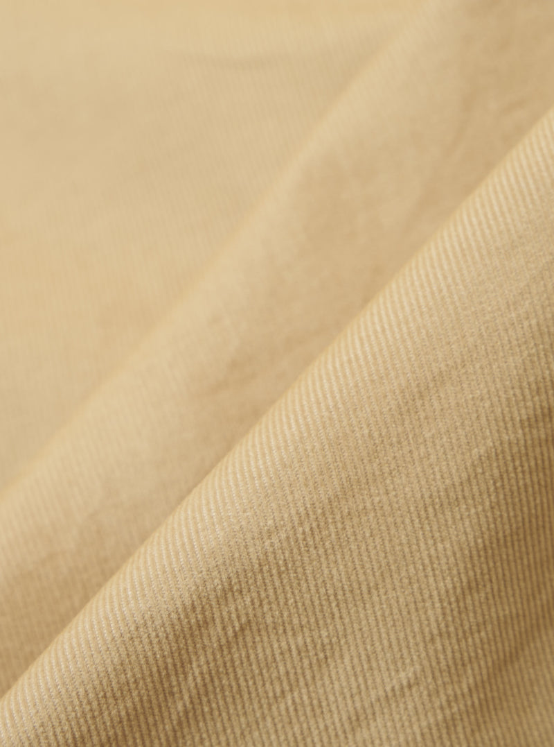 Close-up of the Sand Organic Fine Cord Daybrook Shirt fabric. The fine corduroy texture is visible in a soft, neutral sand color. The fabric is draped to show its texture.