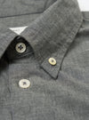 Close-up of the Charcoal Organic Chambray Patched Lazy Day Shirt collar. Shows the charcoal chambray fabric and button details. Shot on a white surface.