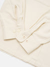 Close-up of the Ecru Sid Flannel CPO Shirt on a white surface. Shows the ecru flannel material, buttoned cuffs, and red stitching detail on the buttons.