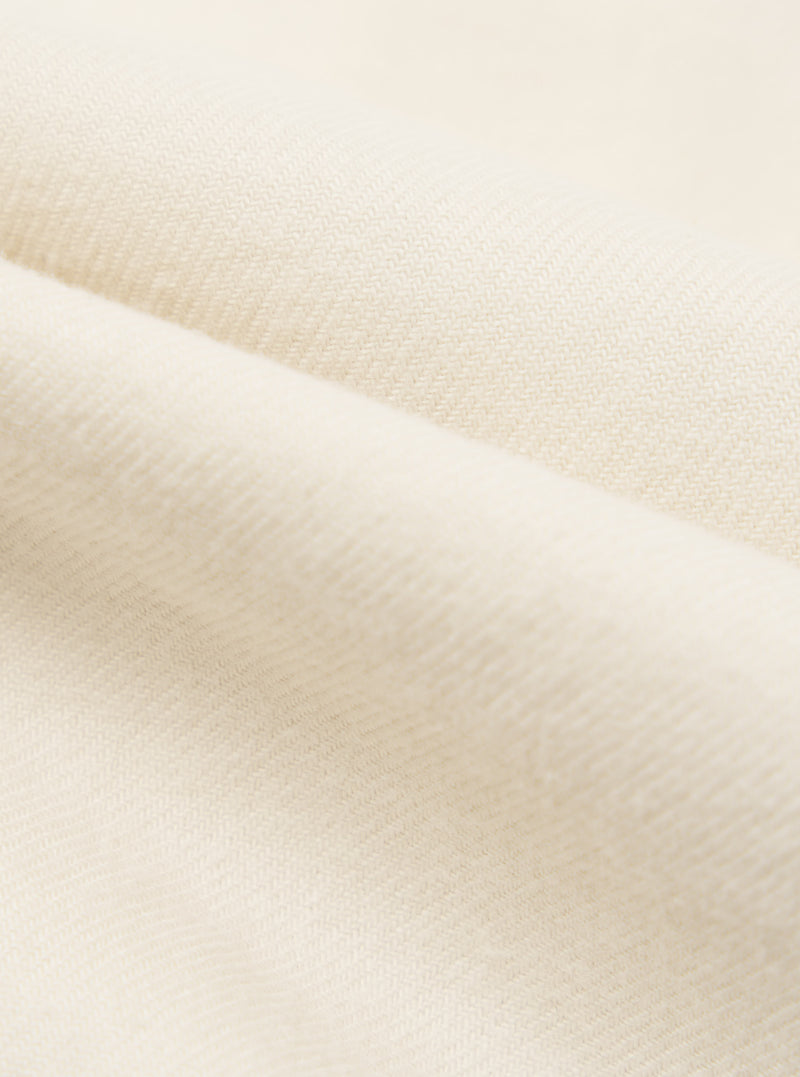 Close-up of the Ecru Sid Flannel CPO Shirt fabric. Soft, ecru-colored flannel material is folded to show texture. Studio shot.