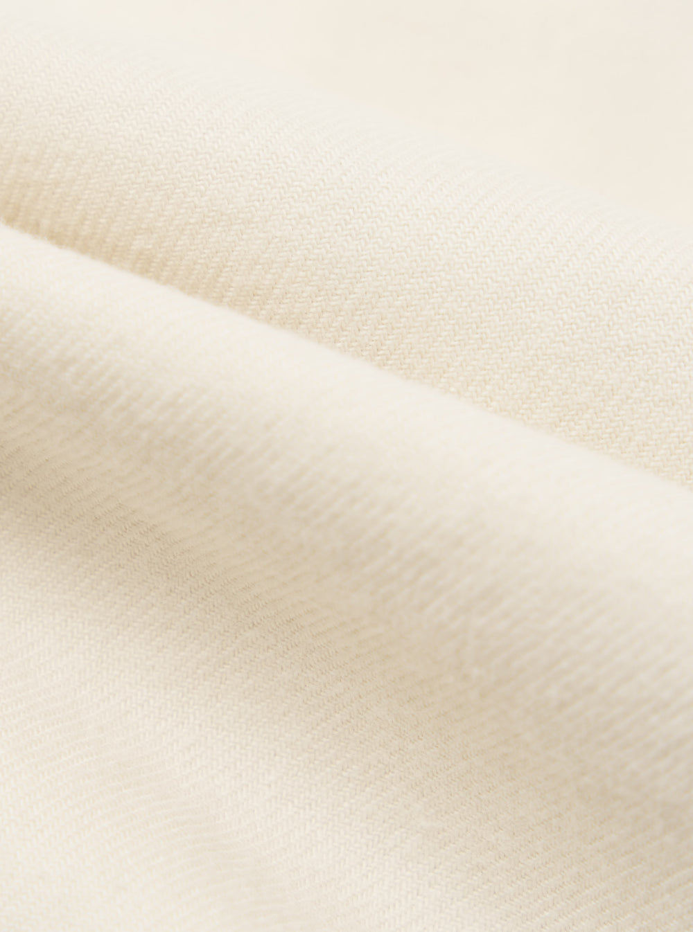 Close-up of the Ecru Sid Flannel CPO Shirt fabric. Soft, ecru-colored flannel material is folded to show texture. Studio shot.
