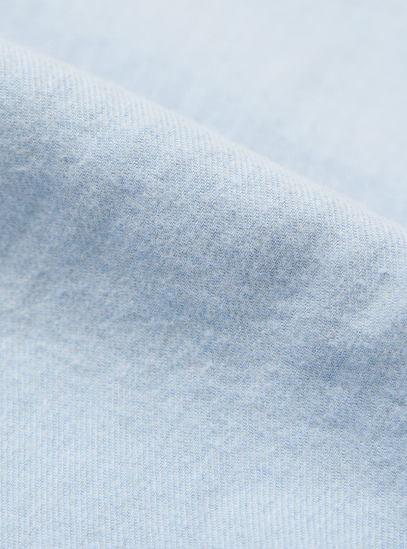 Close-up of the light blue brushed marl twill fabric of the square pocket shirt. The soft texture and subtle pattern are visible against a plain background.