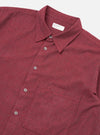 Close-up of the Red Brushed Marl Twill Square Pocket Shirt on a white surface. The shirt is buttoned and features a square pocket. The fabric has a textured, brushed appearance.