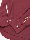 Close-up of the Red Brushed Marl Twill Square Pocket Shirt on a white surface. Shows the texture of the red marl twill, the buttoned cuffs, and the square pocket detail.