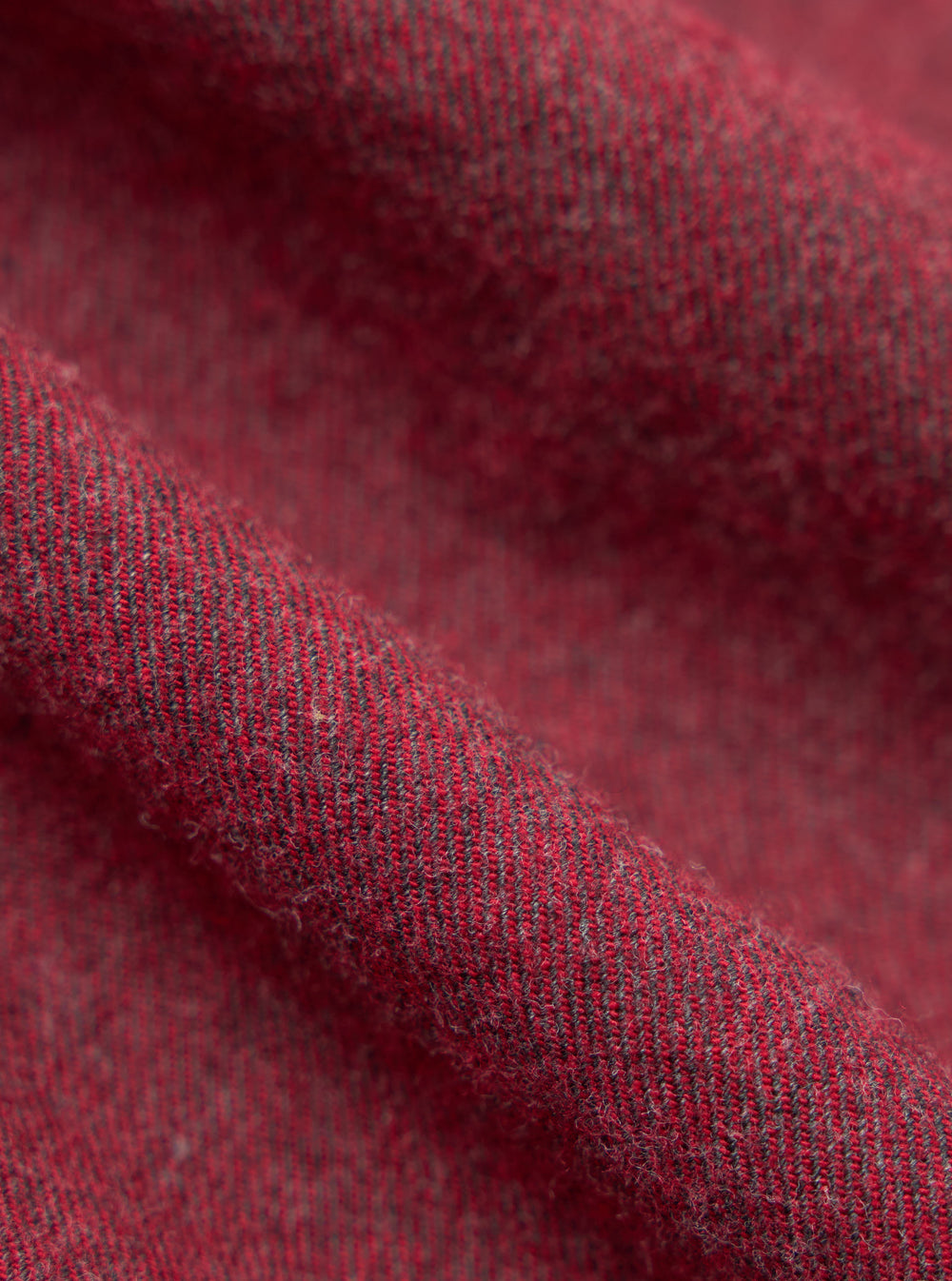 Close-up of the Red Brushed Marl Twill Square Pocket Shirt fabric. The red and grey twill weave is softly draped, showing the texture.