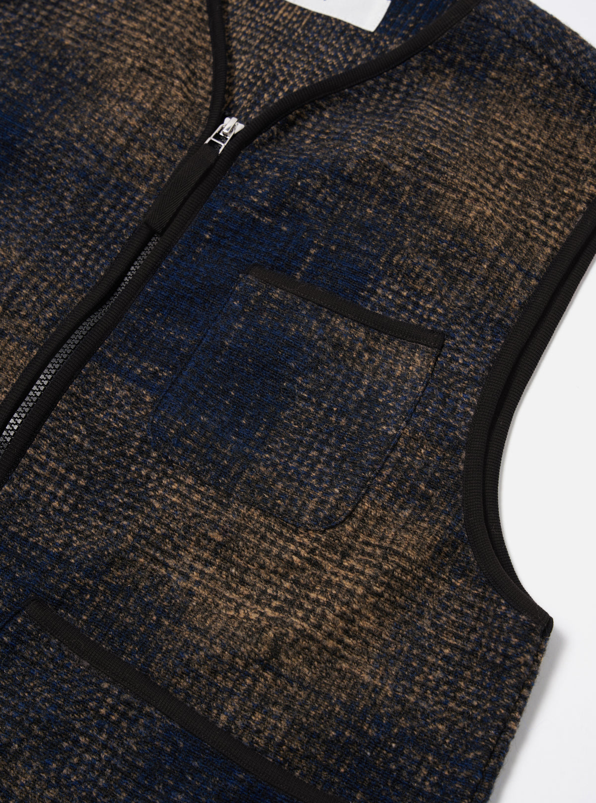 Close-up of the Navy Deca Check Zip Gilet on a white surface. The gilet features a blue and brown check pattern, a zip-up front, and a chest pocket.