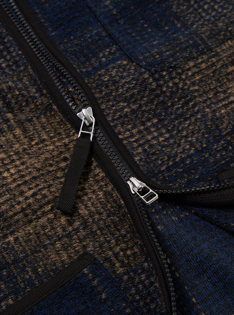 Close-up of the Navy Deca Check Zip Gilet, showcasing its blue and brown checked pattern and black zipper. The image is tightly cropped to highlight the texture and detail.