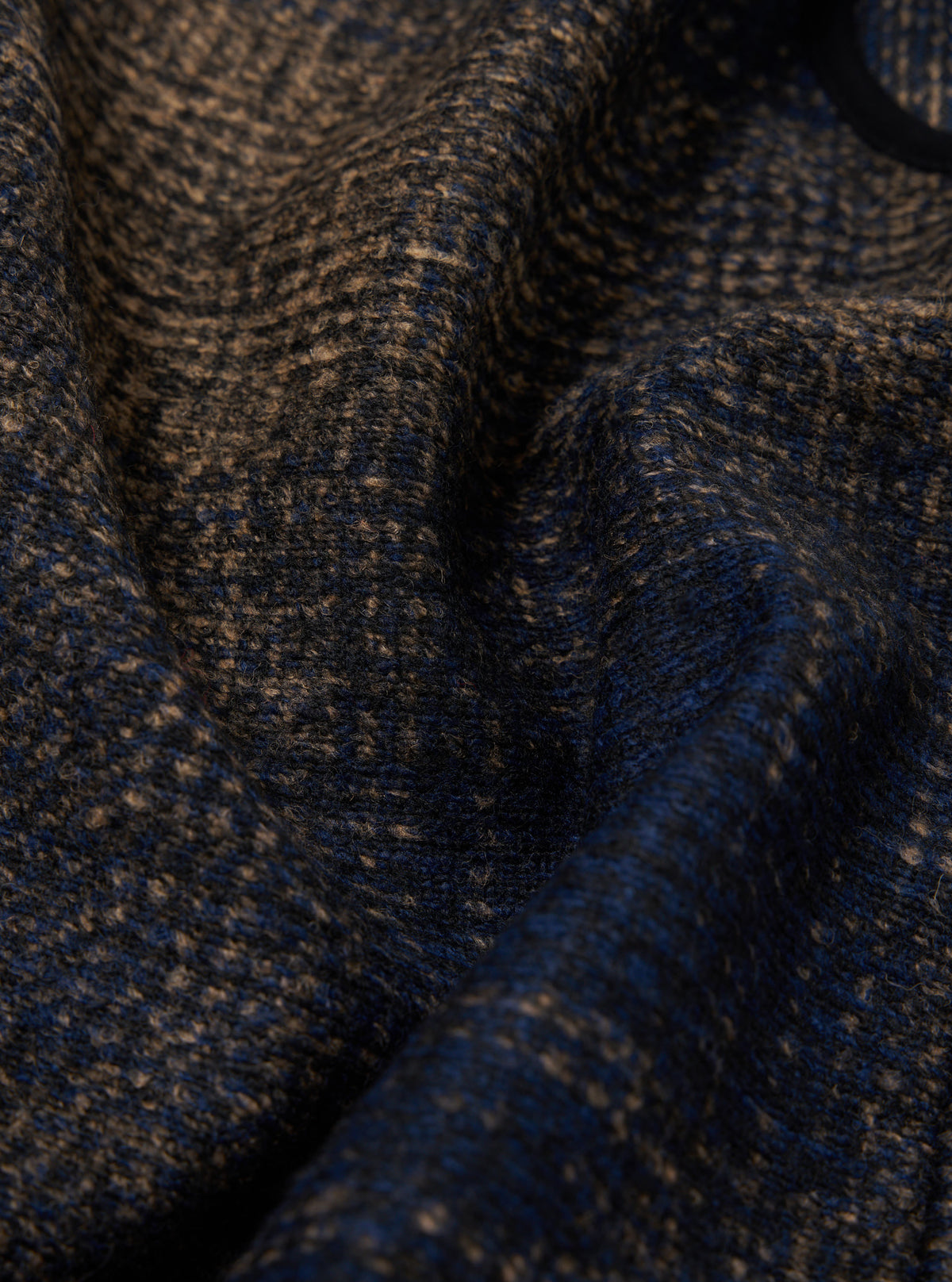 Close-up of the Navy Deca Check Zip Gilet fabric. The material is a textured blend of navy and tan, creating a subtle check pattern. The image focuses on the fabric's texture and color.