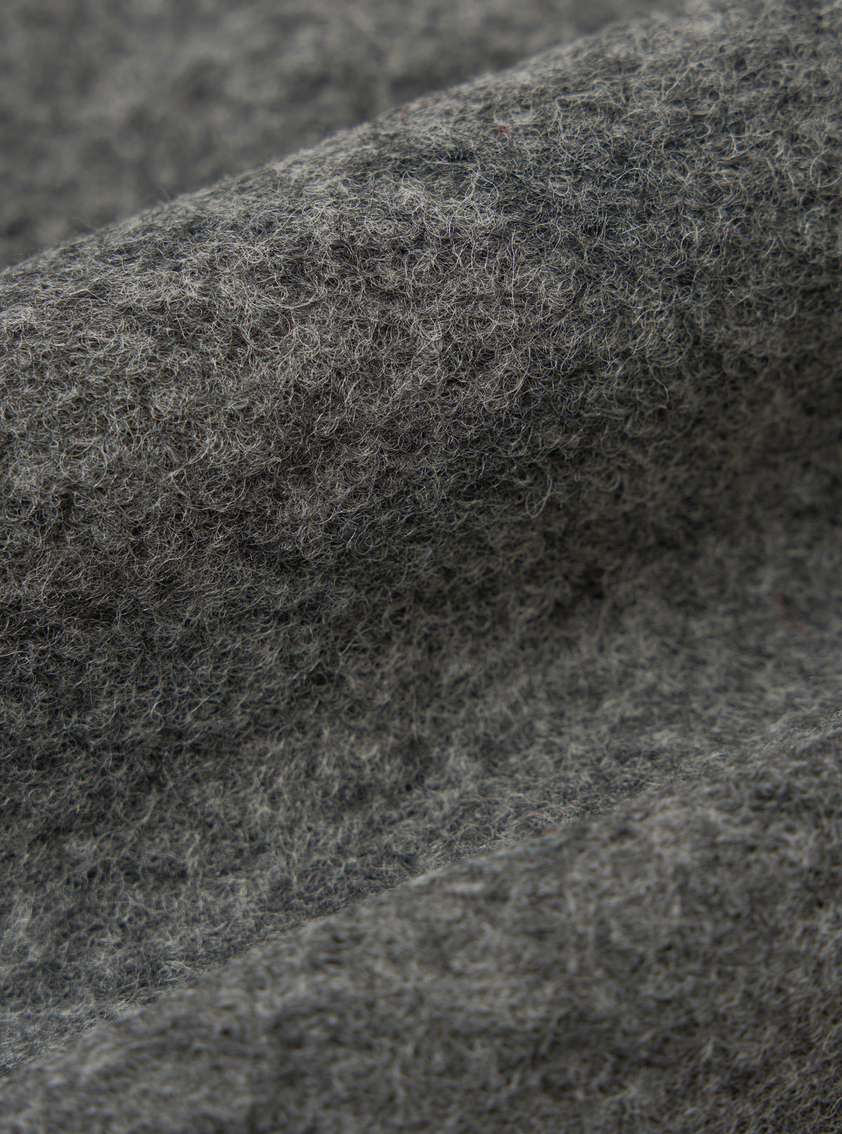 Close-up of the Grey Marl Wool Fleece Advance Cardigan fabric. The soft, textured wool is shown in detail, highlighting its grey marl color and fleece-like texture.