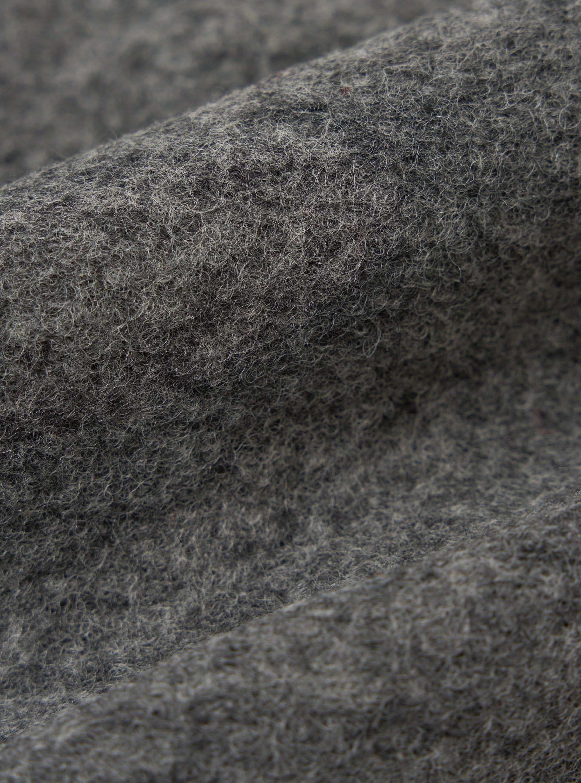 Close-up of the Grey Marl Wool Fleece Advance Cardigan fabric. The soft, textured wool is shown in detail, highlighting its grey marl color and fleece-like texture.