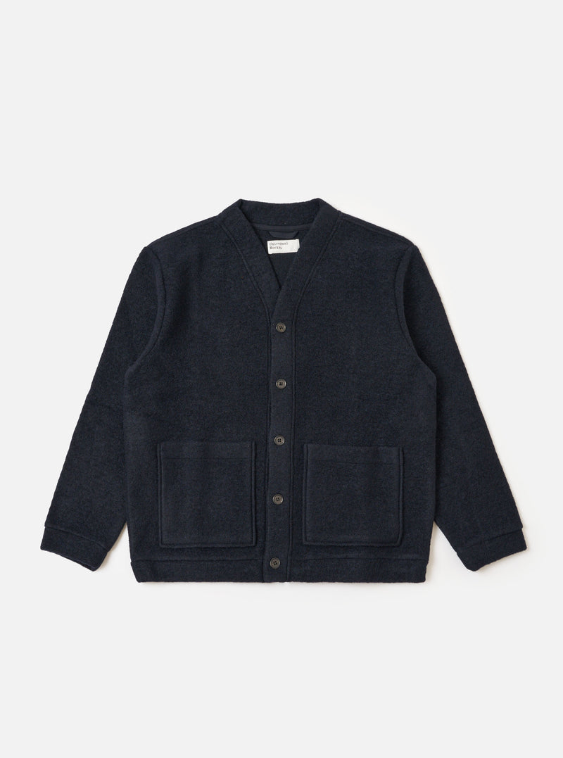 The Navy Wool Fleece Advance Cardigan is displayed on a white background. The cardigan is a dark navy color and made of a soft wool fleece material. It has a relaxed fit and features two front pockets.