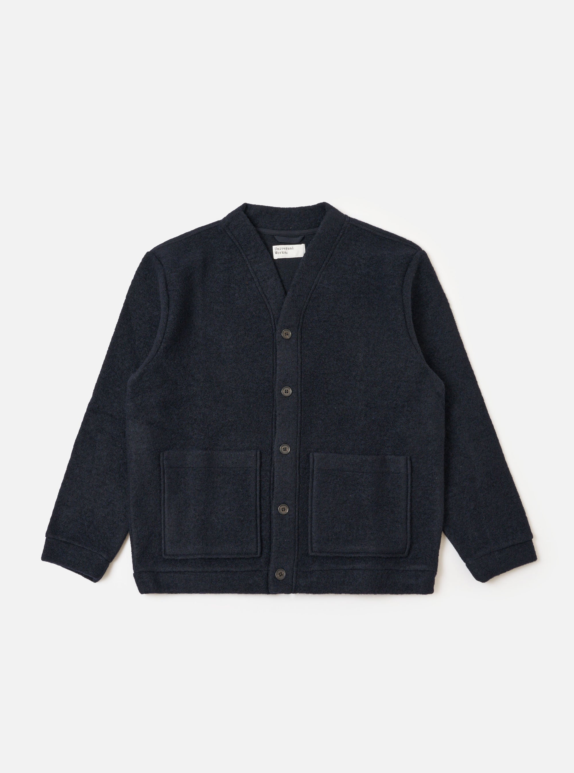 The Navy Wool Fleece Advance Cardigan is displayed on a white background. The cardigan is a dark navy color and made of a soft wool fleece material. It has a relaxed fit and features two front pockets.
