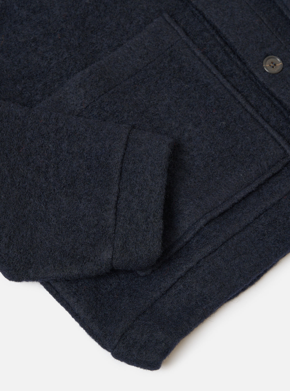 Close-up of the navy wool fleece Advance Cardigan showing the texture and details of the wool material. The cardigan is on a white surface.