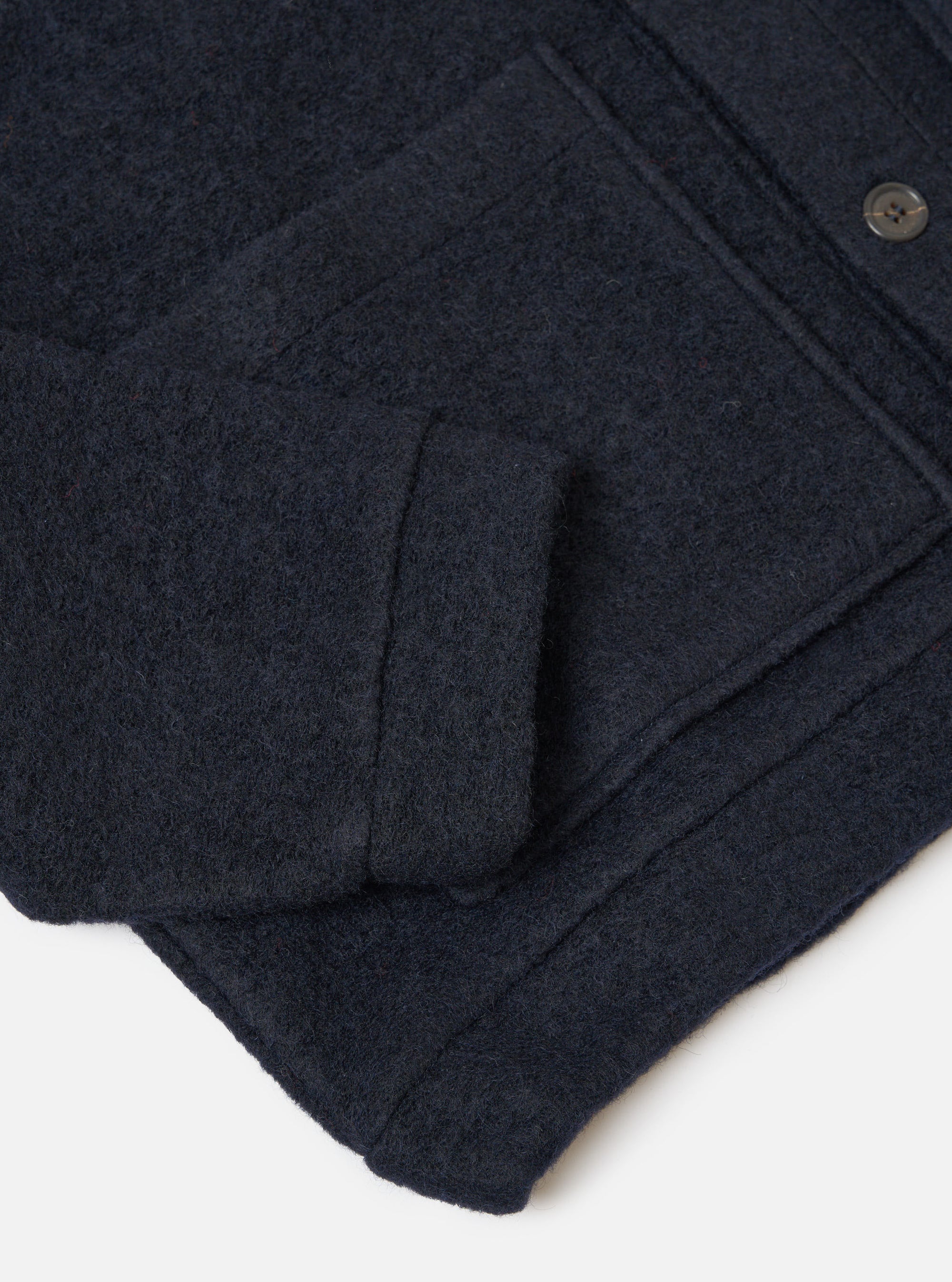 Close-up of the navy wool fleece Advance Cardigan showing the texture and details of the wool material. The cardigan is on a white surface.