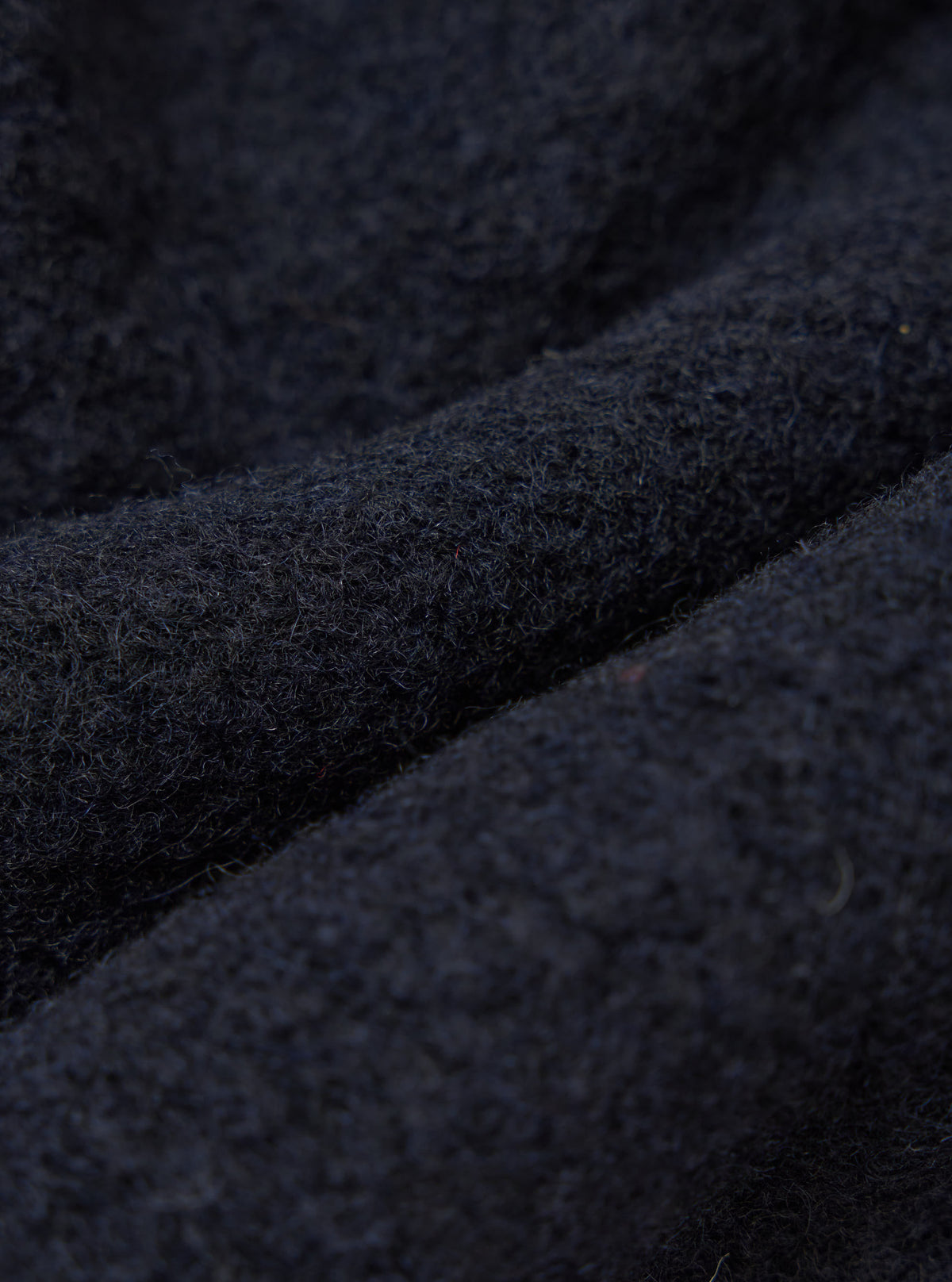 Close-up of the Navy Wool Fleece Advance Cardigan, showing the texture and color of the wool fleece material. The background is a simple, neutral surface.