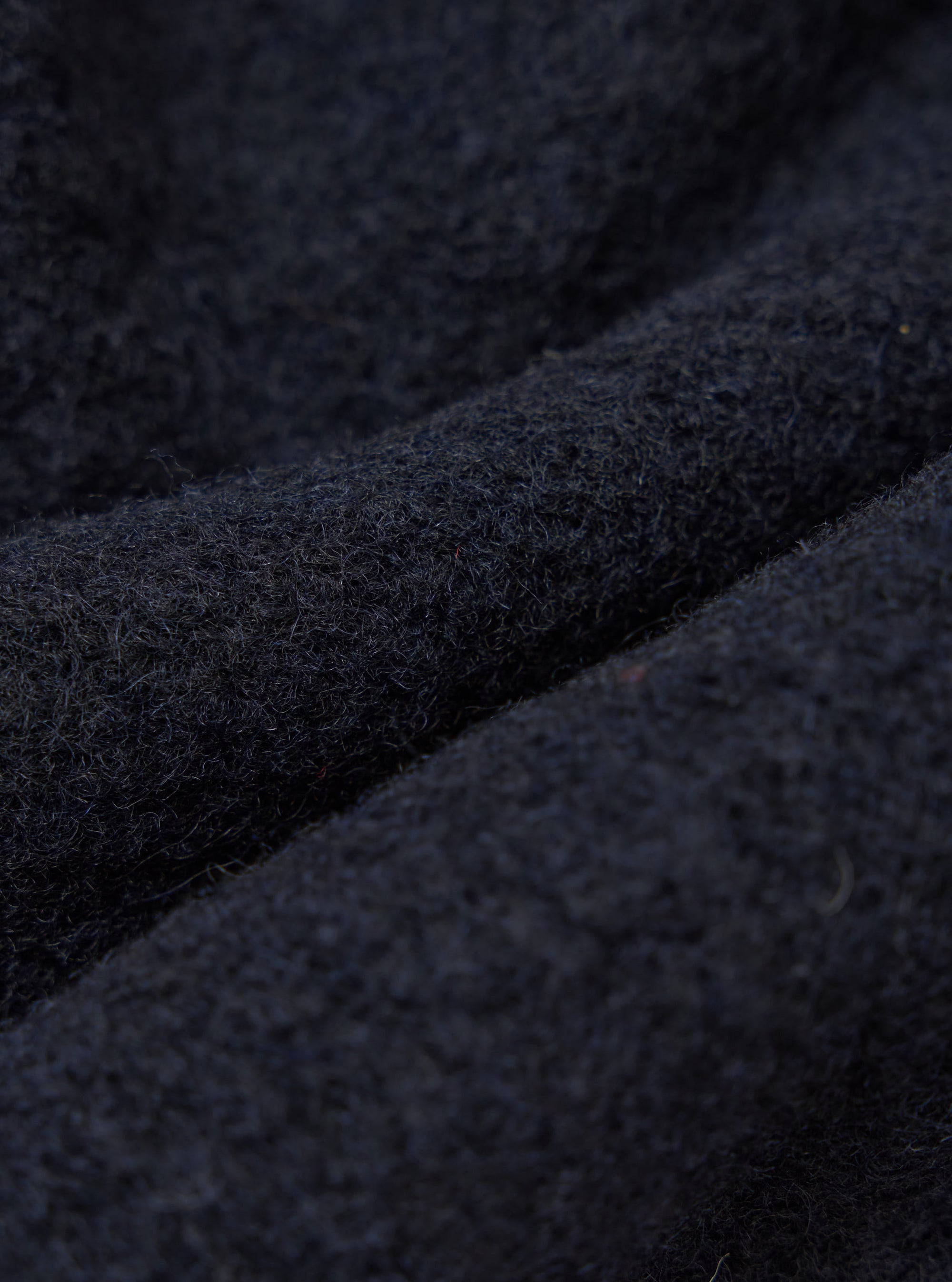 Close-up of the Navy Wool Fleece Advance Cardigan, showing the texture and color of the wool fleece material. The background is a simple, neutral surface.