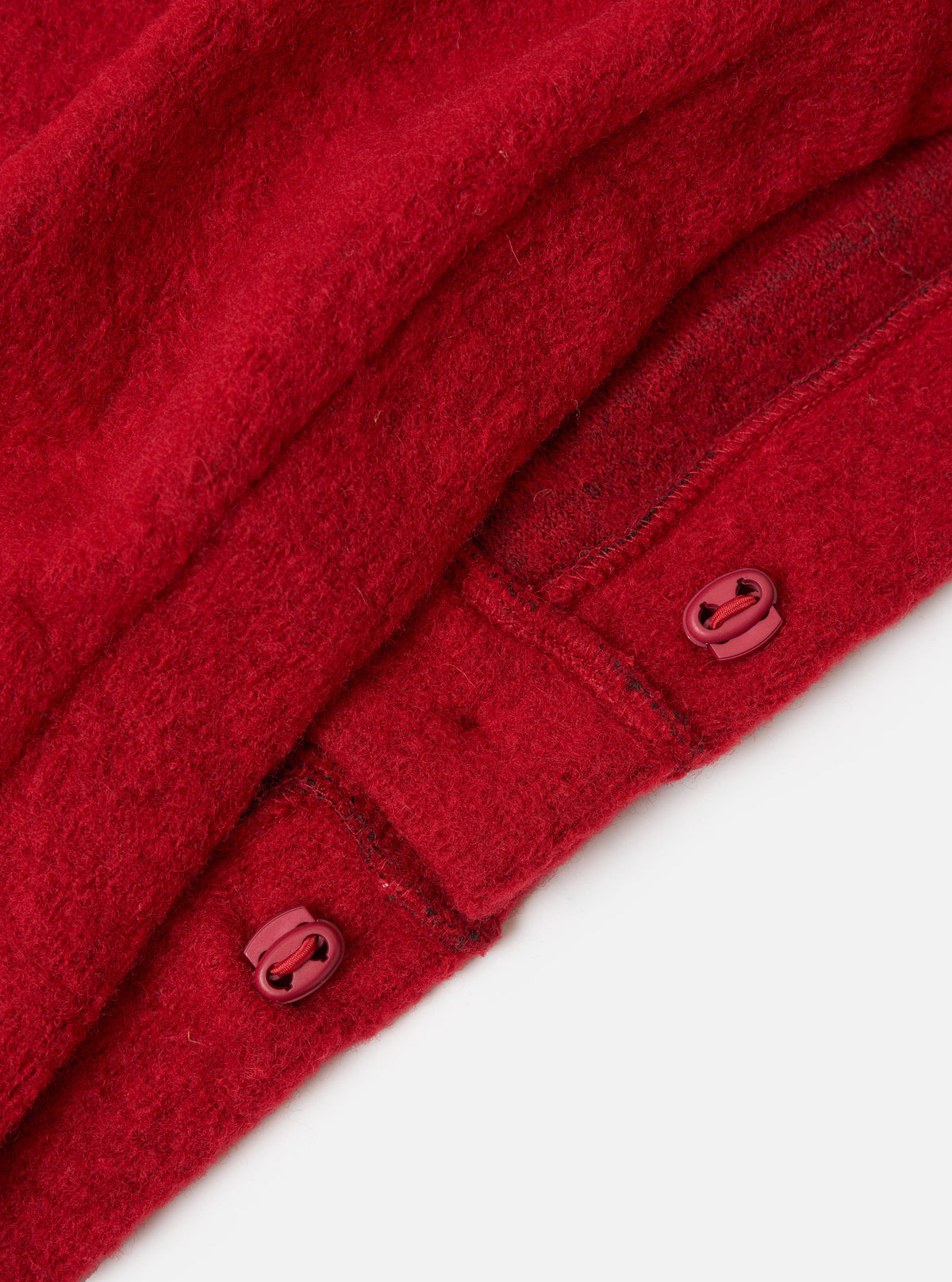 Close-up of the red Wool Fleece Advance Cardigan, showing the wool texture and toggle closures. Shot on a white background.