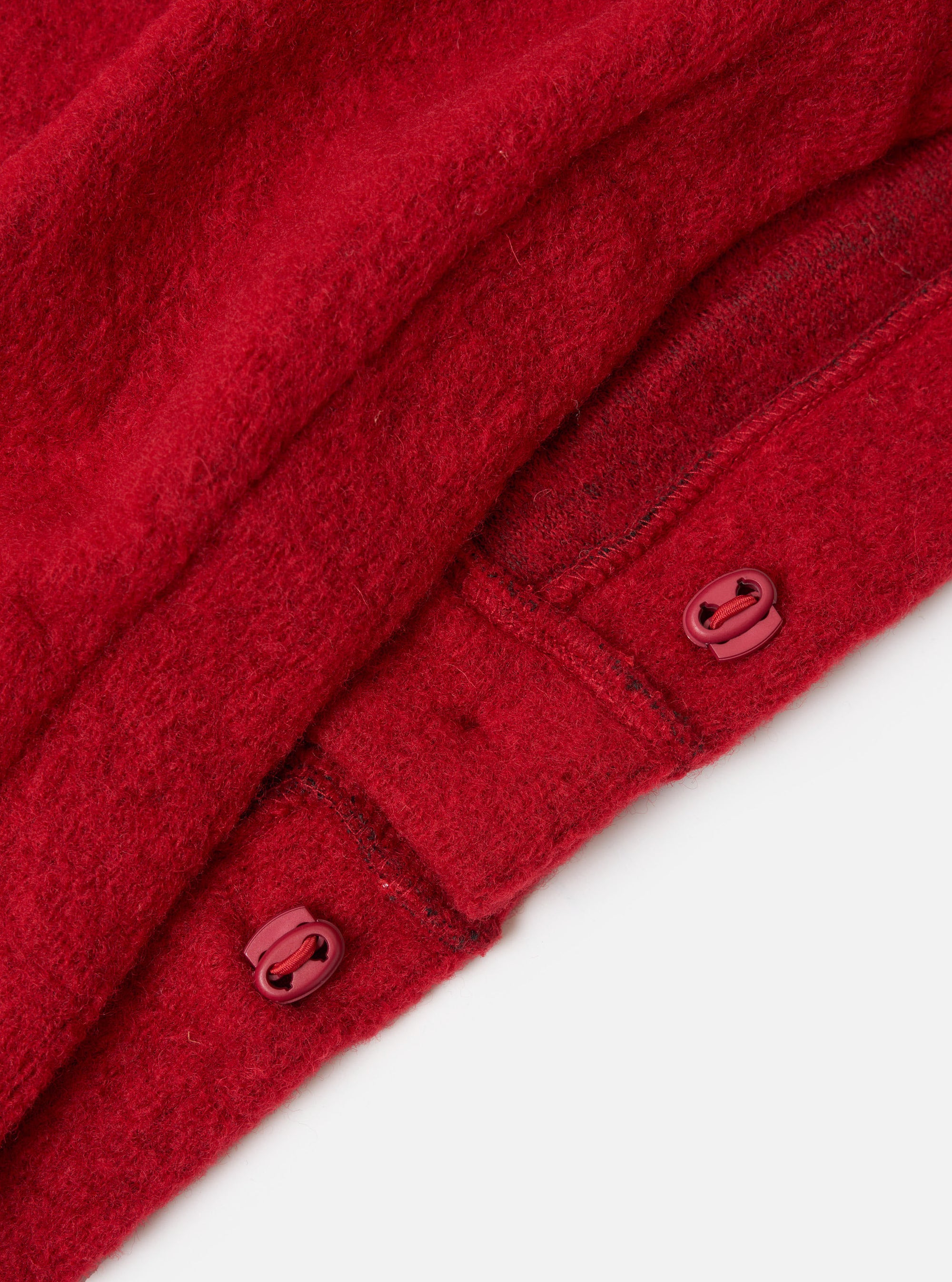 Close-up of the red Wool Fleece Advance Cardigan, showing the wool texture and toggle closures. Shot on a white background.
