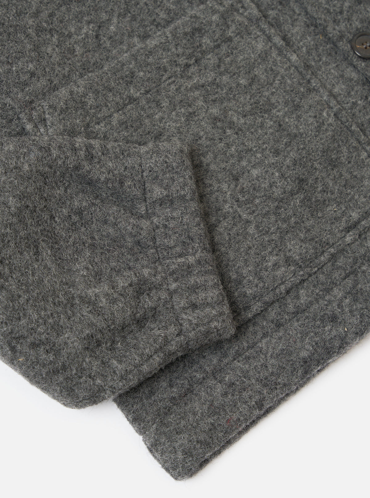Close-up of the Grey Marl Wool Fleece Rams Jacket sleeve on a white surface. The grey wool fleece texture is visible.