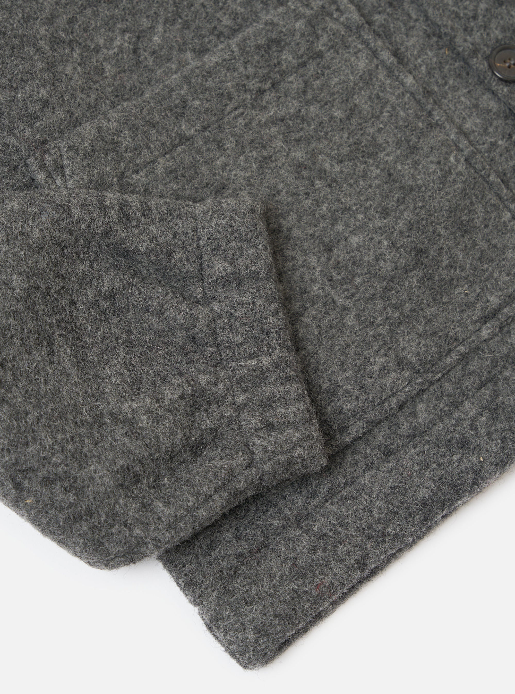 Close-up of the Grey Marl Wool Fleece Rams Jacket sleeve on a white surface. The grey wool fleece texture is visible.