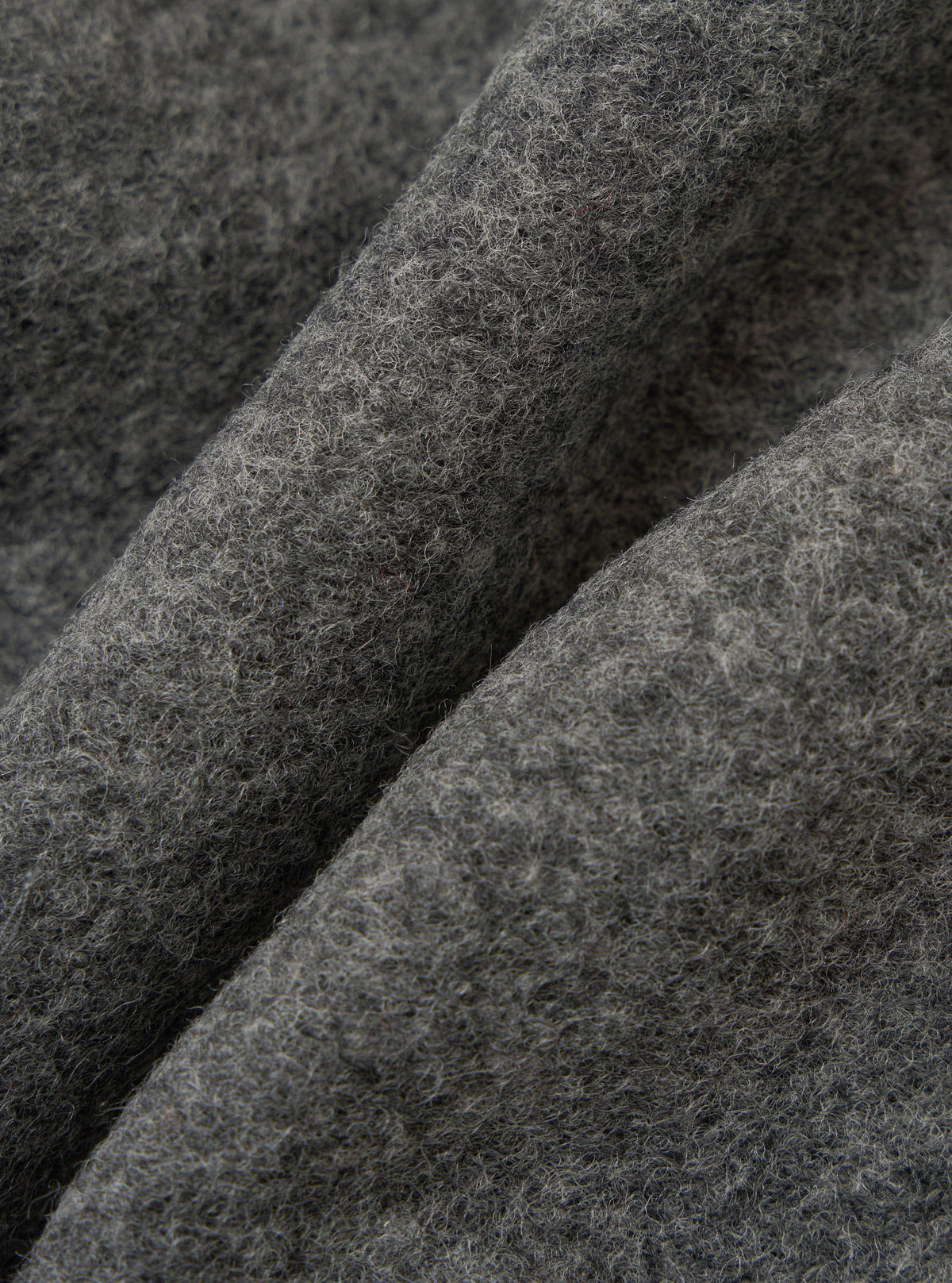 Close-up of the Grey Marl Wool Fleece Rams Jacket fabric. The grey wool has a soft, textured fleece. The background is a simple, neutral surface.