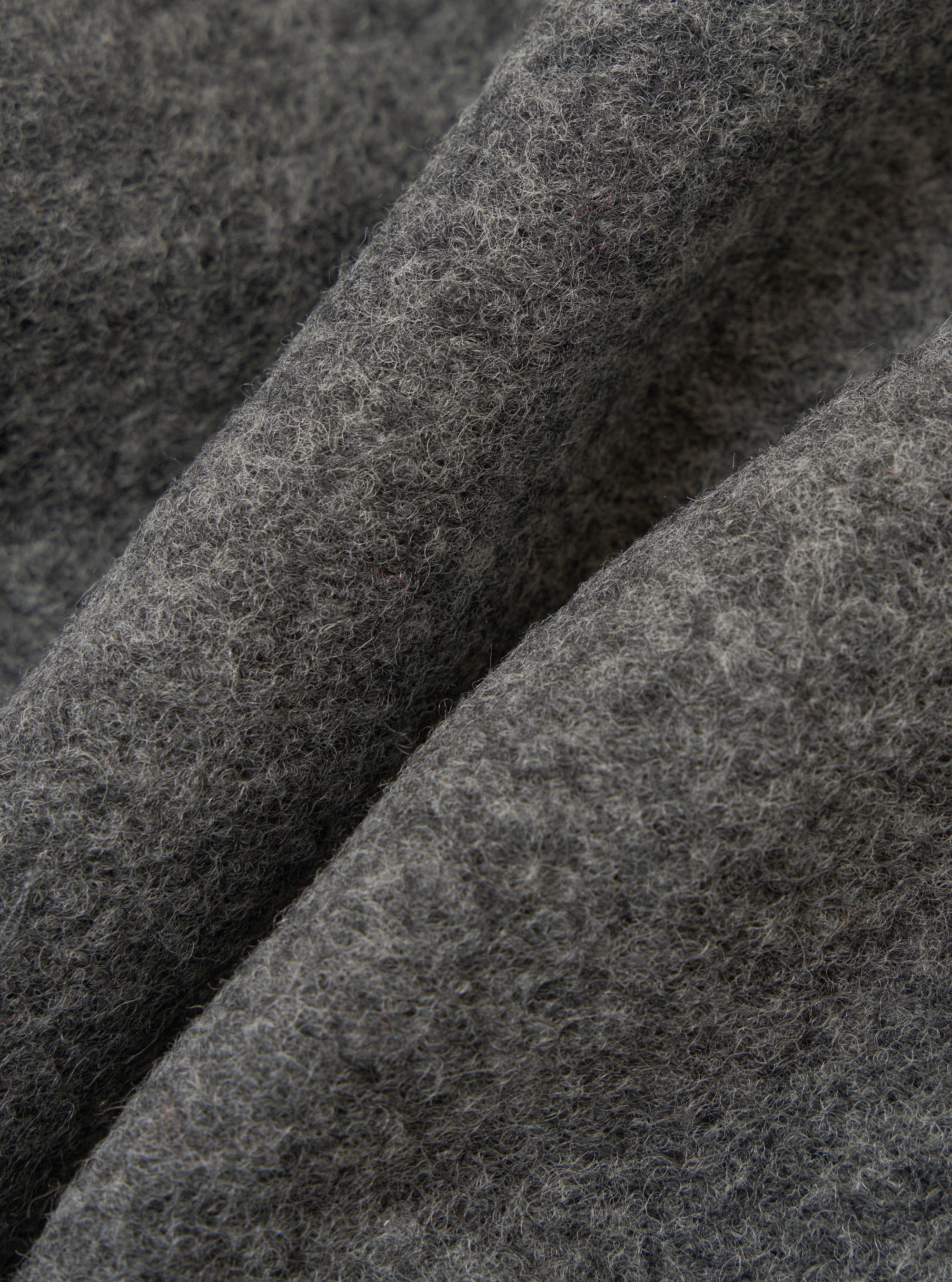 Close-up of the Grey Marl Wool Fleece Rams Jacket fabric. The grey wool has a soft, textured fleece. The background is a simple, neutral surface.
