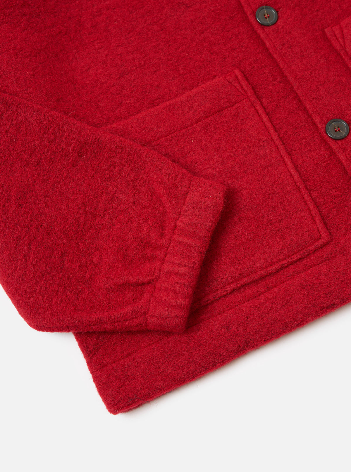 Close-up of the red wool fleece Rams jacket on a white surface, showing the sleeve, pocket, and buttons.