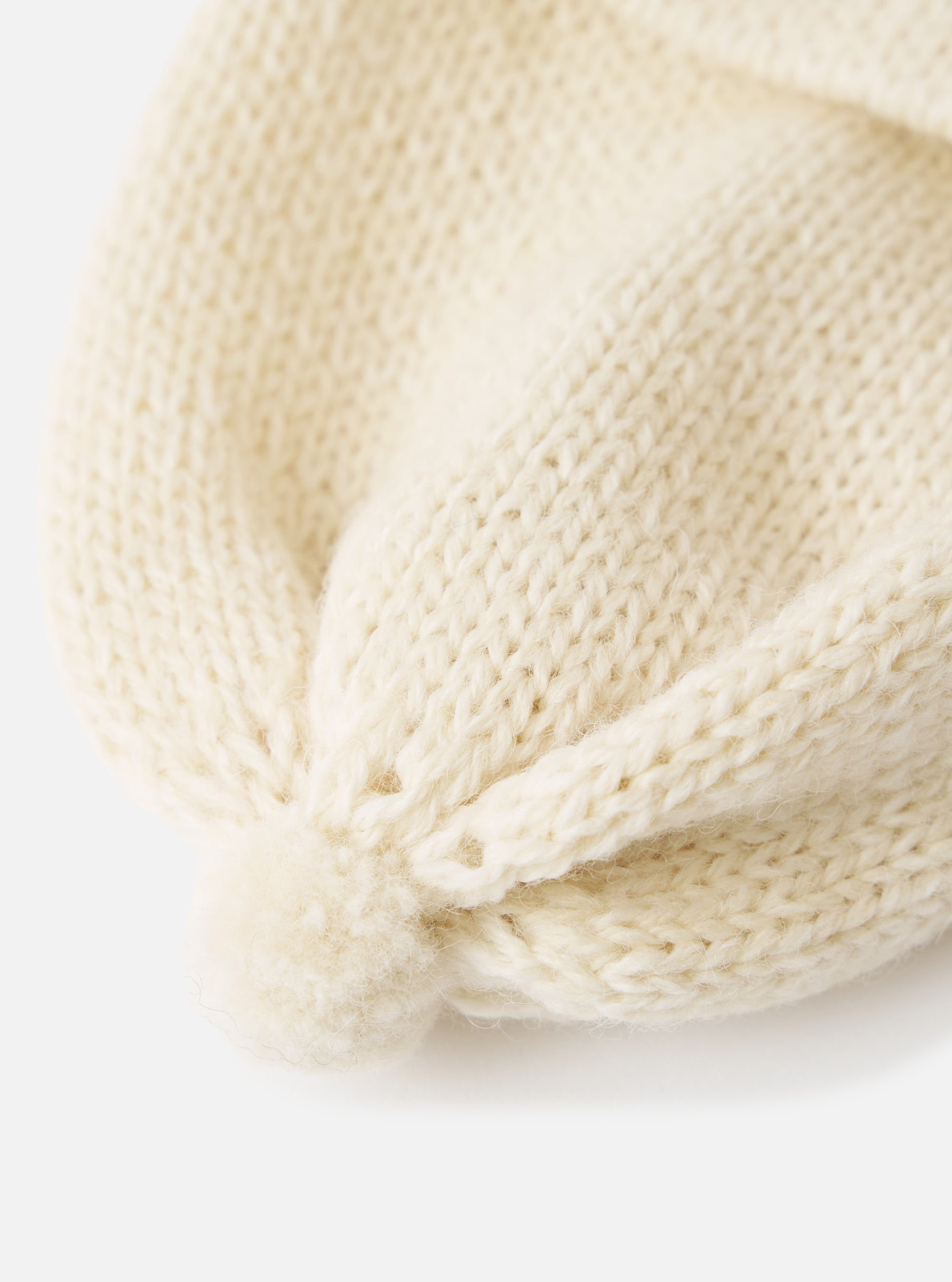 Close-up of the Ecru Alpaca/British Wool Bobble Hat on a white background. The knit is chunky and the color is a soft, creamy ecru. The hat has a small bobble detail.