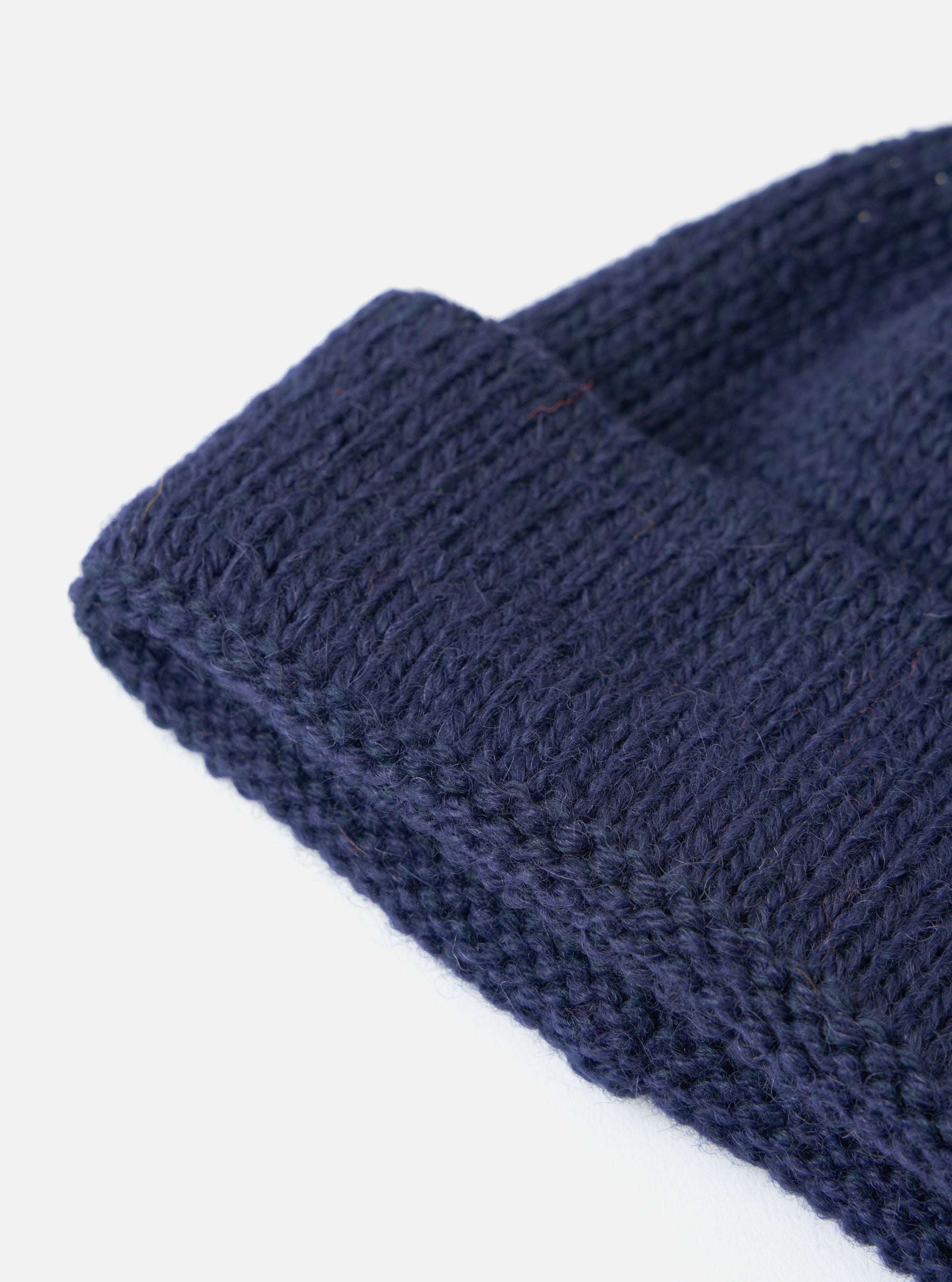 Close up of the Navy Alpaca/British Wool Bobble Hat showing the texture of the knit on a white background.