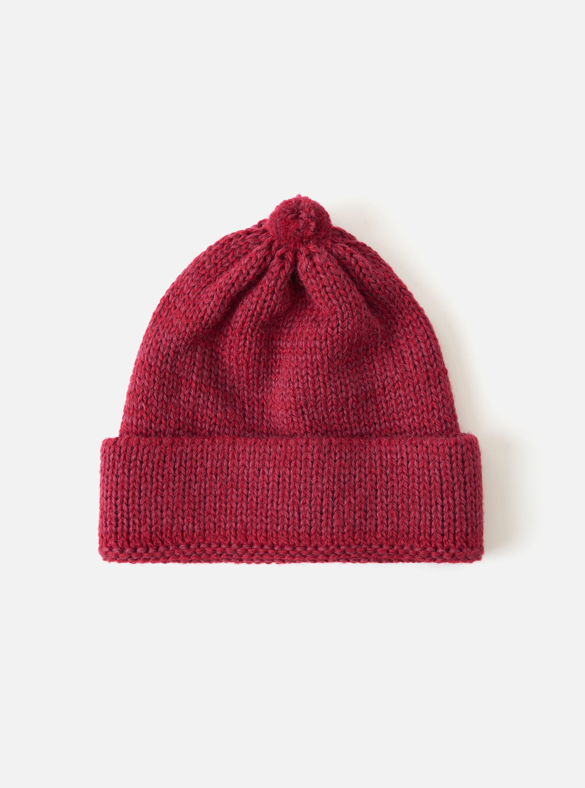 Close-up of a Red Alpaca/British Wool Bobble Hat on a white background. The knitted hat has a bobble on top and a folded brim.
