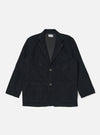 The Black Cat Cord Two Button Jacket in black corduroy, laid flat on a white background. The jacket has two front pockets and a notched lapel.